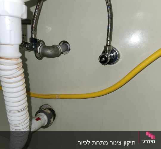 צינורות מתכת וגומי מתחת לכיור